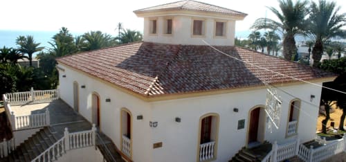 Hostal Juan Carlos en Carboneras, España - edificio blanco con techo de terracota, cúpula, palmeras y vistas al mar