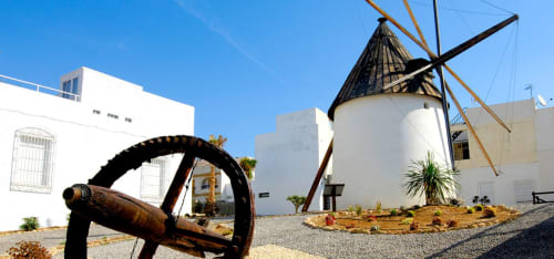 Molino de la hostal Juan Carlos y edificios blancos en Carboneras, España bajo un cielo azul despejado