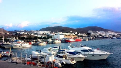 Marina de Carboneras con barcos blancos y azules, montañas y edificios frente al mar bajo cielo despejado