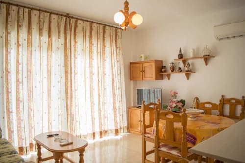 Luminosa sala de estar en Hostal Juan Carlos de Carboneras con muebles de madera, cortinas florales y decoración tradicional