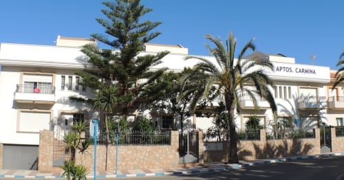 Hostal Juan Carlos, edificio blanco con palmeras y fachada de piedra en Carboneras, España