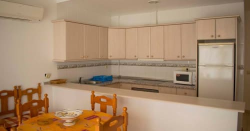 Cocina y comedor del Hostal Juan Carlos en Carboneras con mesa de madera, muebles beige y electrodomésticos de acero inoxidable