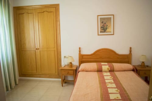 Habitación del Hostal Juan Carlos en Carboneras con muebles de madera y ropa de cama terracota