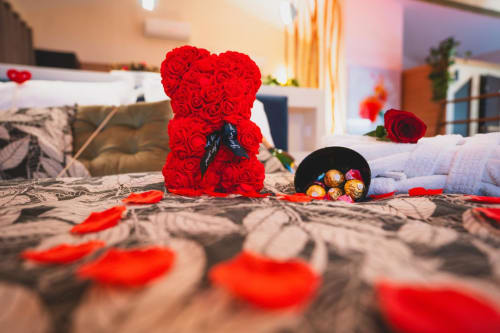Ours en peluche rose rouge avec chocolats sur le lit de la Suite l'Olive Sacrée à l'hôtel de luxe provençal