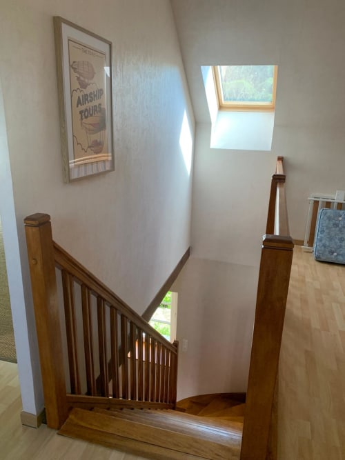 Palier d'escalier du gîte Accolade à Châteaudun avec rampes en bois et fenêtre de toit