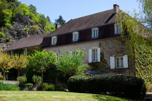 Hotel Moulin Renaudiots in Autun, Frankrijk: stenen manor met mansardedak omgeven door weelderige tuinen