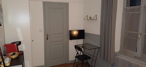 Camera moderna presso il Relais Saint-Laurent B&B a Chevreuse con scrivania, televisione, sedia nera e pavimentazione in parquet