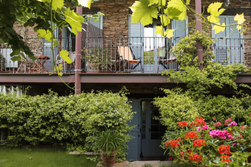 Casa Rural La Perla cottage garden with blooming red and pink flowers, brick building with balcony and lush greenery