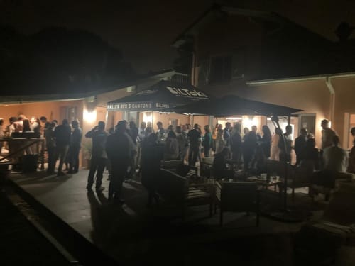 Evening gathering at La Conciergerie Biarritz with guests mingling under black umbrellas on patio