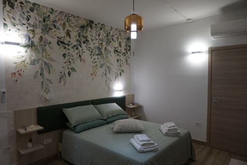 Camera moderna a La Dimora Di Ipno a Vallata con carta da parati floreale, letto matrimoniale, lampada a sospensione e vista montagna