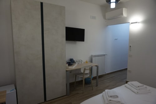 Camera moderna a La Dimora Di Ipno a Vallata con scrivania, TV, armadio e parete blu in primo piano
