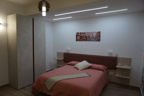 Camera moderna a La Dimora Di Ipno a Vallata con biancheria bordeaux, testata marrone, comodini in legno e design contemporaneo