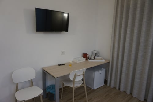 Zona lavoro in camera d'hotel con scrivania, sedie, TV, minibar e tende a La Dimora Di Ipno, Vallata