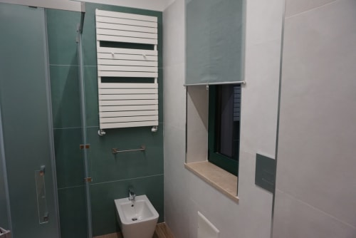 Bagno moderno di La Dimora Di Ipno con piastrelle verdi, portasciugamani bianco, lavabo a colonna e doccia
