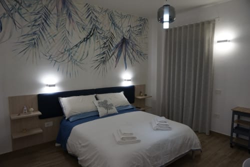 Camera moderna a La Dimora Di Ipno con biancheria bianca, accenti blu, luci a sospensione e vista sulle montagne a Vallata, Italia