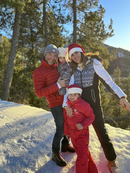 Famiglia che celebra il Natale alla stazione sciistica di Montgenèvre con lo sfondo di una foresta di pini innevata