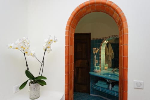 Orchidées blanches près d'une porte en terre cuite voûtée menant à la salle de bains aux carrelages turquoise de la Villa Marina Di Cavu, Bonifacio