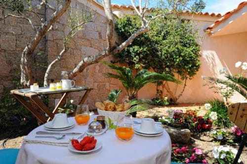 Table de petit-déjeuner en plein air à Villa Marina Di Cavu à Bonifacio avec jus d'oranges frais et corbeille de pains et viennoiseries