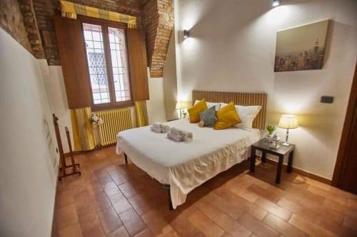 Camera spaziosa dell'hotel L.H.A. srl a Ferrara con letto matrimoniale, accenti gialli, pavimenti in cotto e comfort moderni