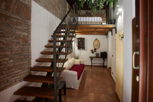 Modern loft entryway in Ferrara with wooden staircase, exposed brick, cream sofa, and decorative accents