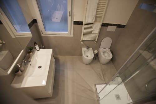 Modern bathroom in LikeHome cottage, Ferrara: white fixtures, bidet, toilet, sink, skylight, and shower area.