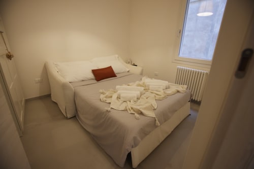 Bedroom in LikeHome San Romano cottage, Ferrara, with bed, sofa, and cream linens displayed on mattress
