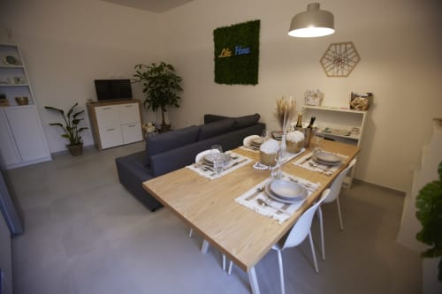 Modern open-plan dining and living area at LikeHome San Romano cottage in Ferrara with wooden table, black sofa, and city