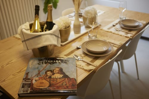 Elegant dining table at LikeHome San Romano in Ferrara with champagne, place settings, and table book