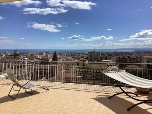 Terrazza sul tetto dell'Aparthotel Bentivoglio a Catania con lettini, vista mare e skyline della città