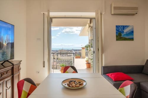 Salotto moderno all'Aparthotel Bentivoglio di Catania con terrazza aperta affacciata sui colori vivaci dello skyline cittadino