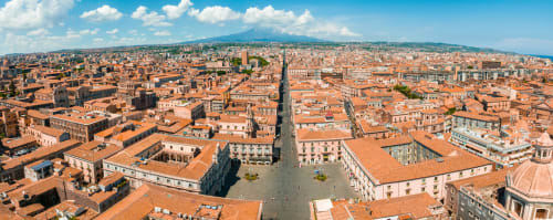 Vue aérienne des bâtiments aux toits orangés et des rues historiques de Catania, avec l'Etna en arrière-plan, Sicile Italie