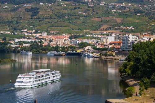 Cruise ship on Douro River with Valença do Douro town and vineyards in background