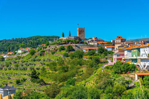 Hillside village with colorful buildings and medieval castle tower overlooking Valença do Douro, Portugal
