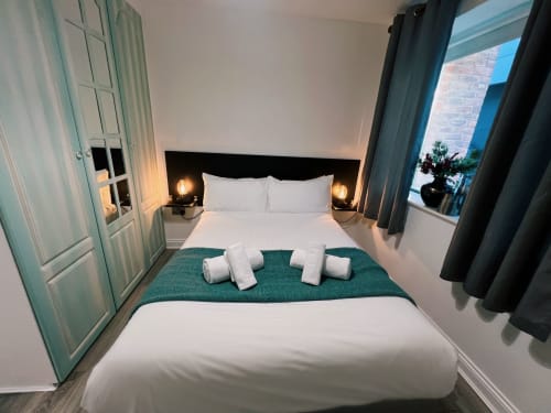 Modern Dublin hotel bedroom with white bedding, black headboard, ambient lighting, and teal accents at Exchange Suites Temple