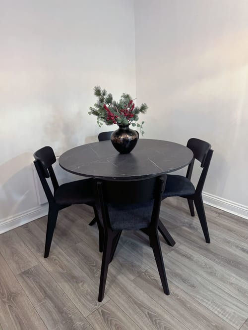 Modern round black marble dining table with four black chairs and floral arrangement in Dublin apartment