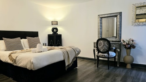 Modern bedroom in Dublin Exchange Suites 2-bedroom apartment with black bed, cream bedding, hardwood floors, and sitting