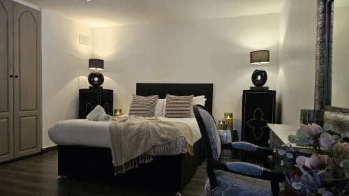 Luxury bedroom at Dublin Exchange Suites with black bed, neutral bedding, twin nightstands with lamps, hardwood floors, and