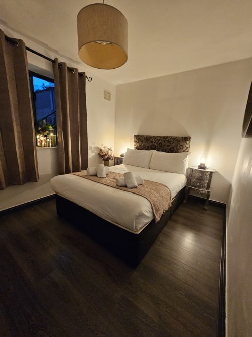 Modern bedroom at Dublin Exchange Suites with queen bed, wooden pendant light, hardwood floors, and balcony access