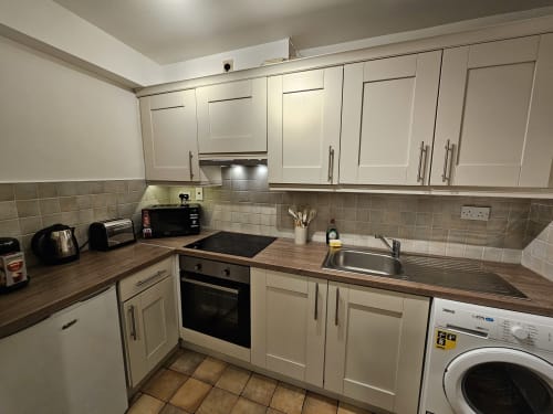 Modern kitchen in Dublin Exchange Suites 2-bedroom apartment with cream cabinets, wooden countertops, built-in oven, and