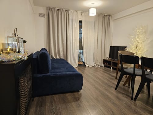 Modern living room in Dublin Exchange Suites 2-bedroom apartment with navy sofa, dining area, and balcony access.