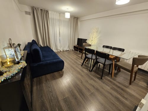 Dublin Exchange Suites 2-bedroom apartment living area with navy sofa, dining table, TV, and modern hardwood floors.