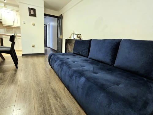 Dark blue sofa in Dublin Exchange Suites apartment living area with hardwood floors and open-plan layout