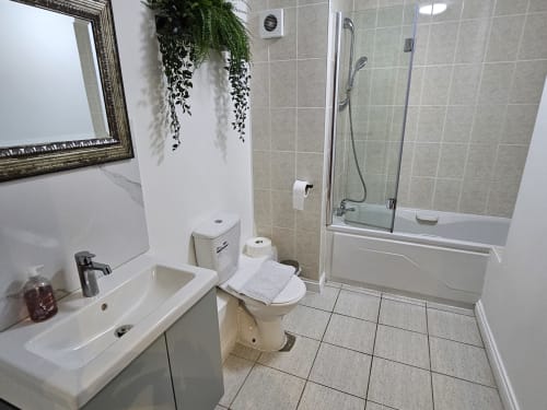 Modern bathroom at Dublin Exchange Suites with sink, toilet, bathtub, and shower enclosure