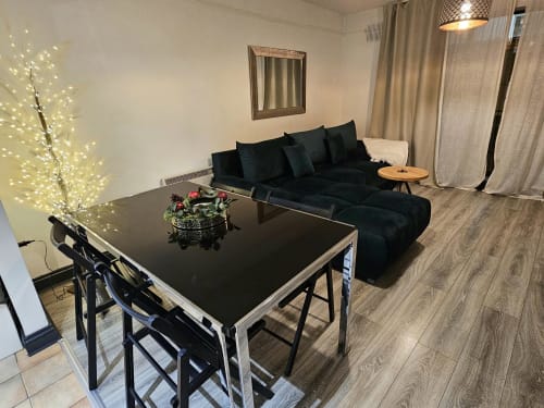 Modern Dublin apartment living room with black sofa, dining table, illuminated branch décor, and hardwood floors at Exchange