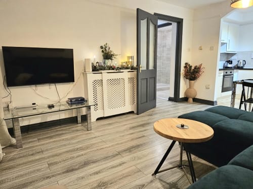 Modern Dublin Exchange Suites family suite with kitchen, living area, flat-screen TV, wooden floors, and teal sofa