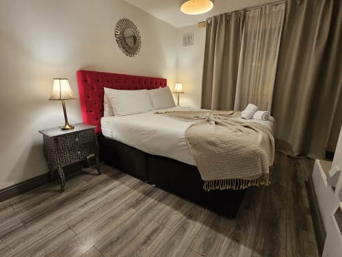 Modern bedroom in Dublin Exchange Suites with red headboard, white bedding, and hardwood floors
