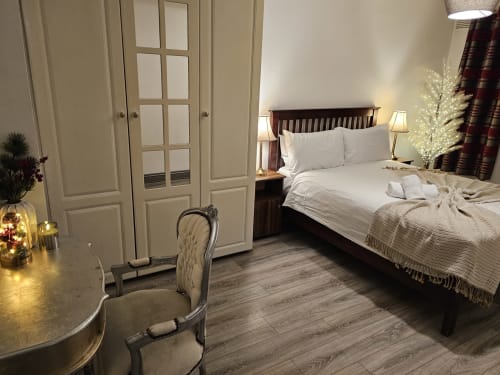 The Liffey Suite bedroom at Dublin Exchange Suites featuring a dark wood bed with white linens, cream wardrobe, desk area,