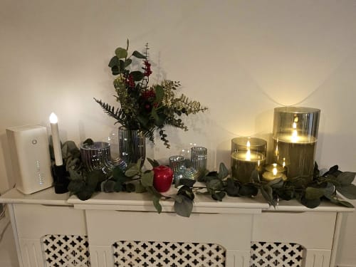 Fireplace mantel with lit candles, fresh flowers, greenery garland, and red ornament in The Liffey Suite