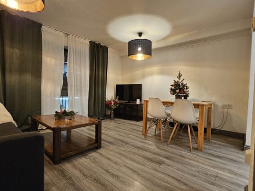 The Liffey Suite living area at Dublin Exchange Suites with dining table, sofa, TV, hardwood floors, and holiday decorations.