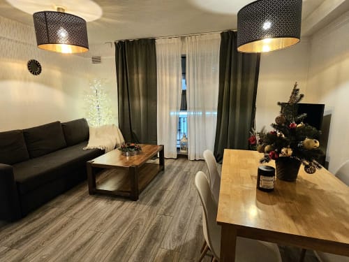 Dublin Exchange Suites Liffey Suite living area with black sofa, wooden dining table, Christmas tree, and modern pendant